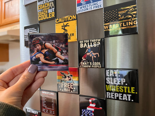 Hand holding a custom wrestling photo magnet in front of a fridge covered in wrestling-themed magnets