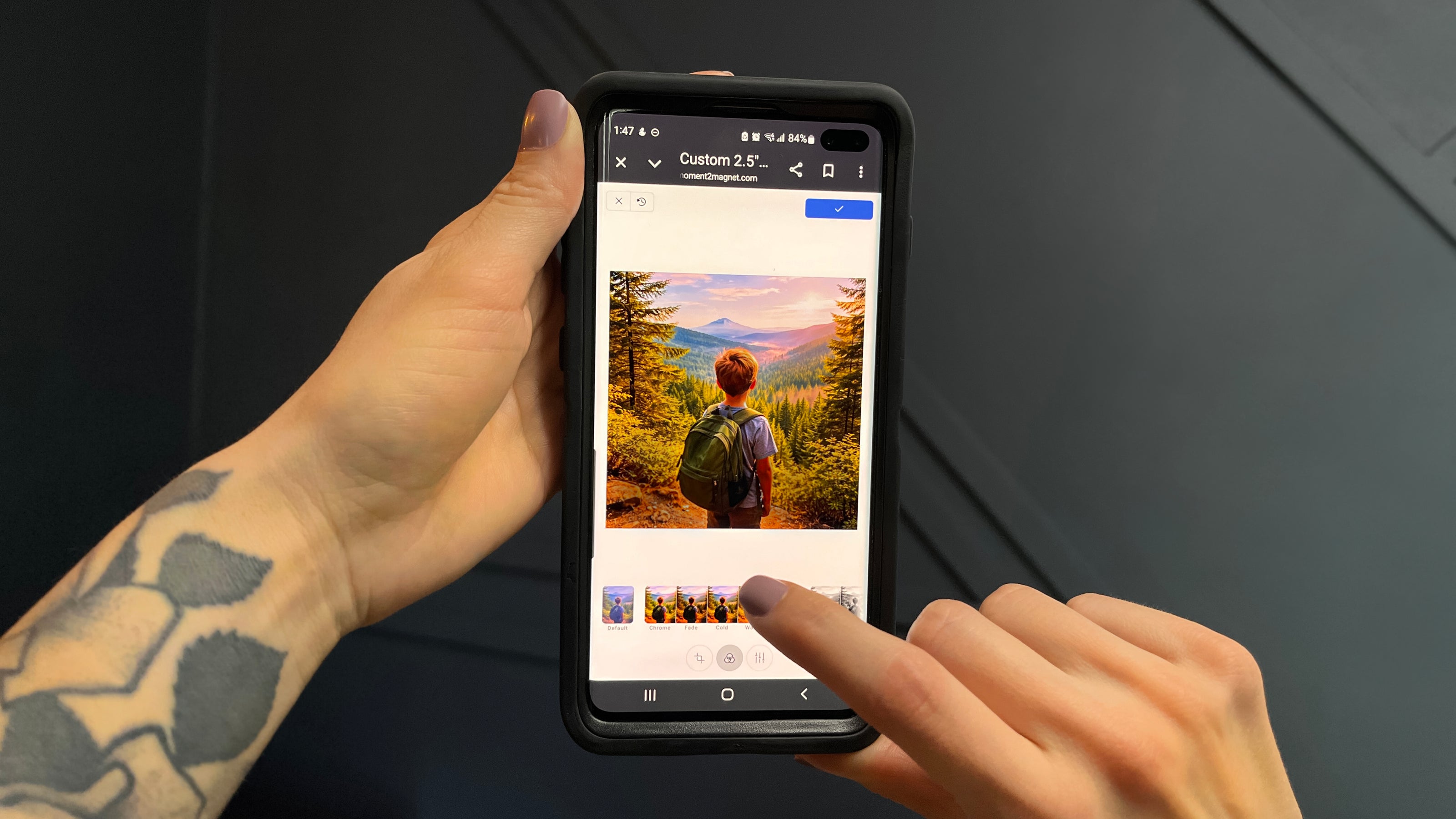 Hand holding a phone showing a photo being uploaded and cropped for a custom magnet
